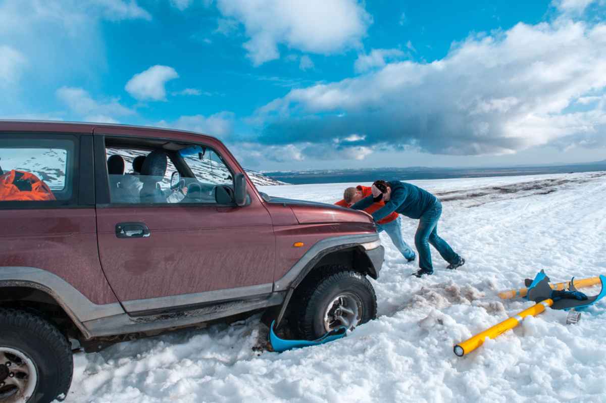 Eine Gruppe von M&auml;nnern versucht, ein 4x4-Fahrzeug zu befreien, das im Schnee feststeckt.