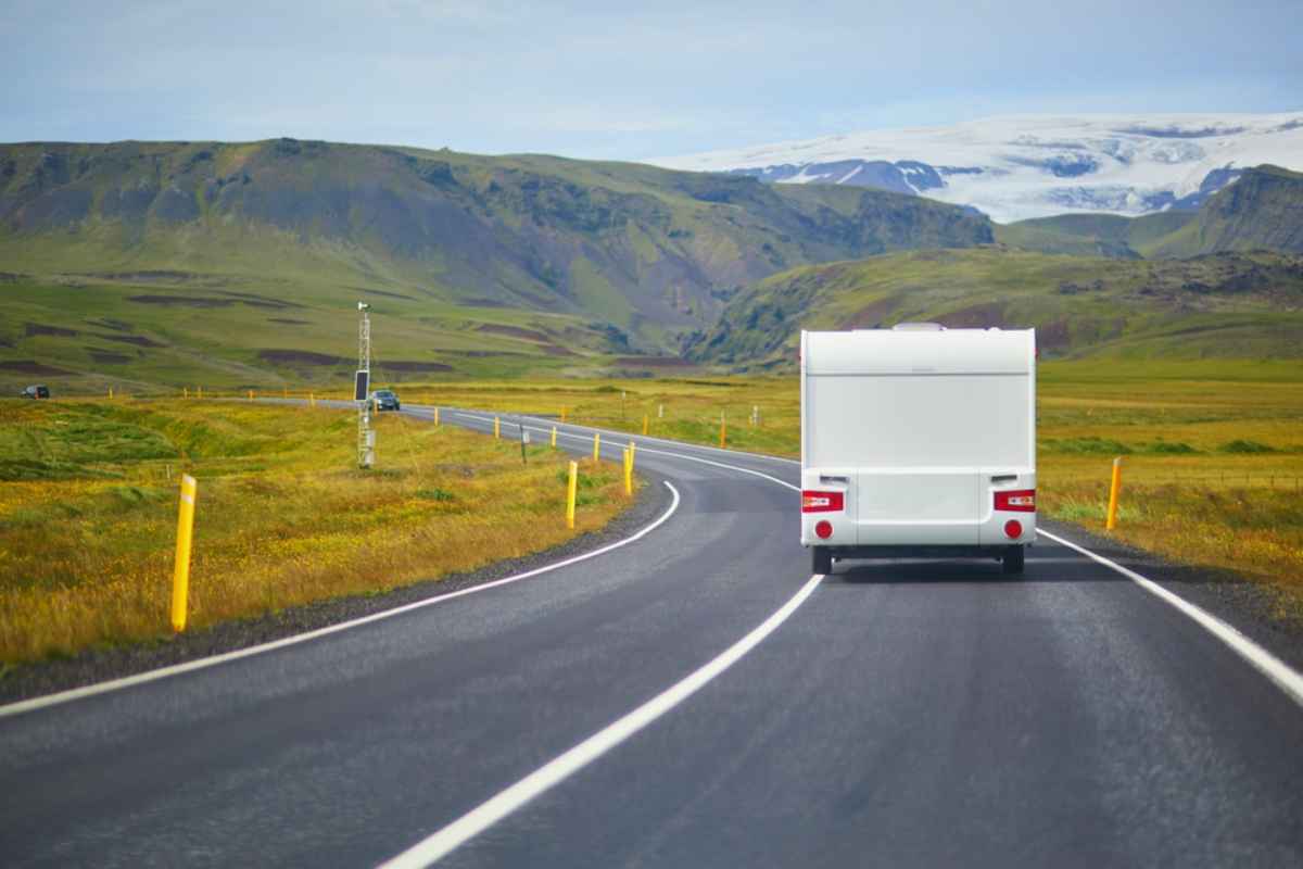 Ein wei&szlig;er Camper f&auml;hrt entspannt auf einem klaren, farbenfrohen Abschnitt der isl&auml;ndischen Ringstra&szlig;e.